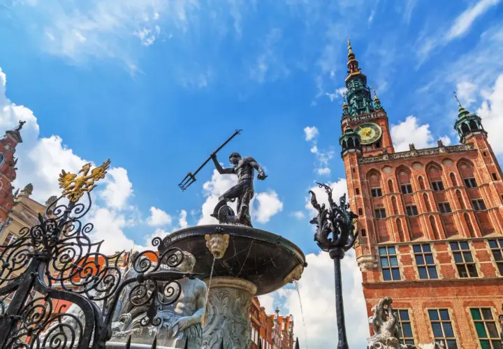 Fontanna Neptuna i Ratusz Głównego Miasta w Gdańsku Stare Miasto, pod błękitnym niebem.
