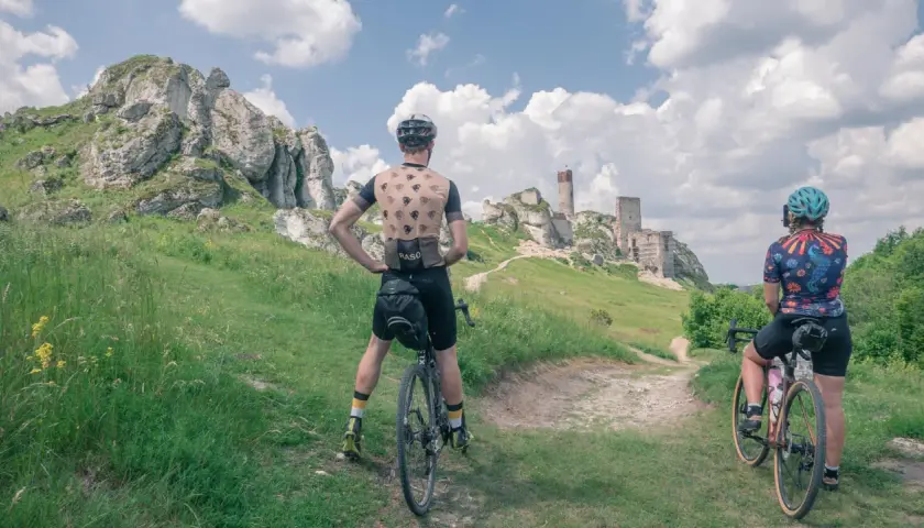 Dwaj rowerzyści podziwiają ruiny zamku na szlaku rowerowym Orlich Gniazd.