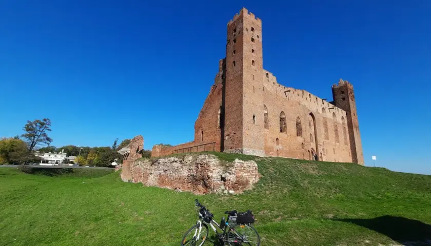 Ruiny zamku w Grudziądzu na tle błękitnego nieba. Rower z sakwami czeka na dalszą podróż.