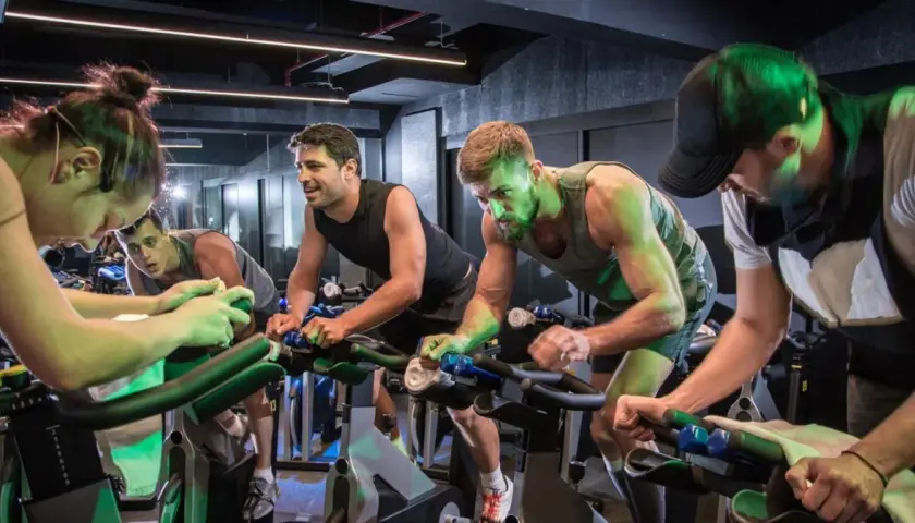 Intensywny trening spinningowy. Ludzie na rowerach stacjonarnych, skupieni na wysiłku.