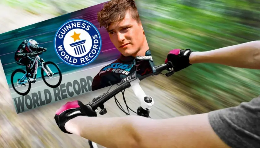 Kolarz w rękawiczkach i kasku pędzi na rowerze, celując w rekord prędkości na rowerze. Obok logo Guinness World Records.