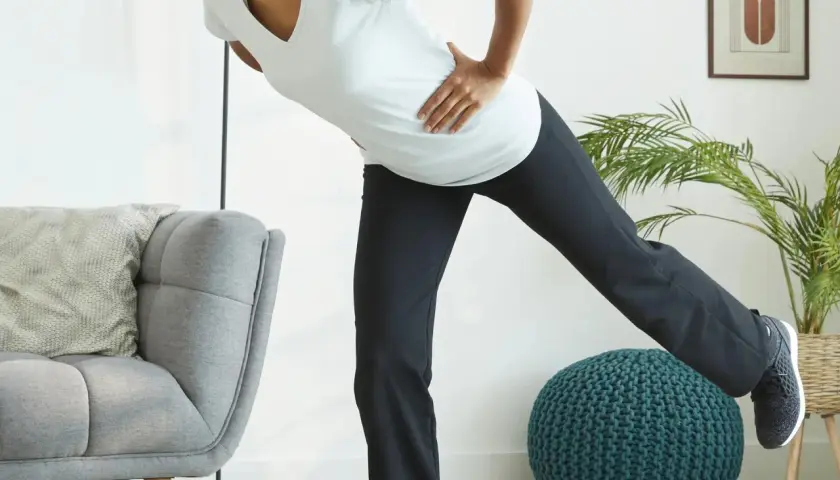 Kobieta w ciąży ćwiczy pilates, unosząc nogę. Dba o formę i dobre samopoczucie.