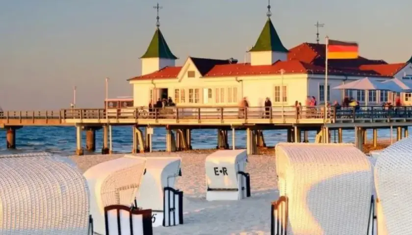 Plaża w Ahlbecku z molo i białymi koszami plażowymi. To popularne atrakcje nad Bałtykiem.
