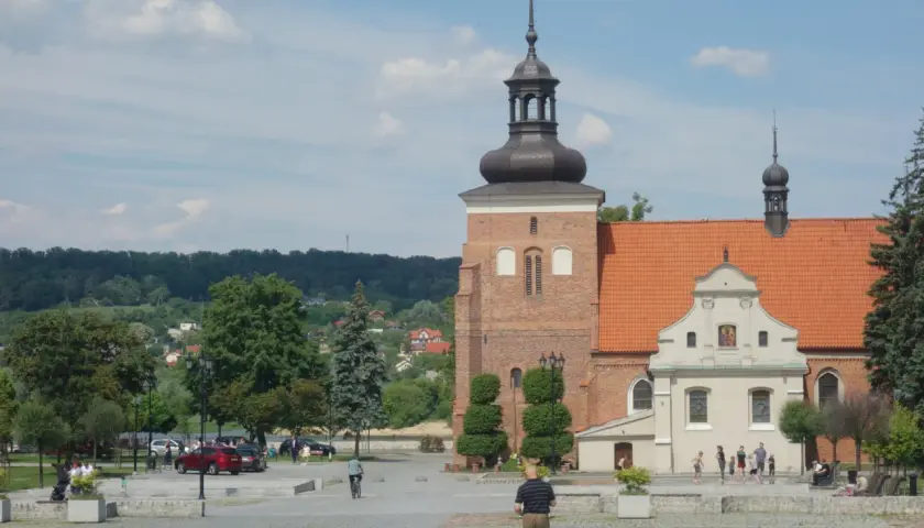 Włocławek atrakcje na weekend: plac z katedrą, zielone drzewa i ludzie spacerujący w słoneczny dzień.