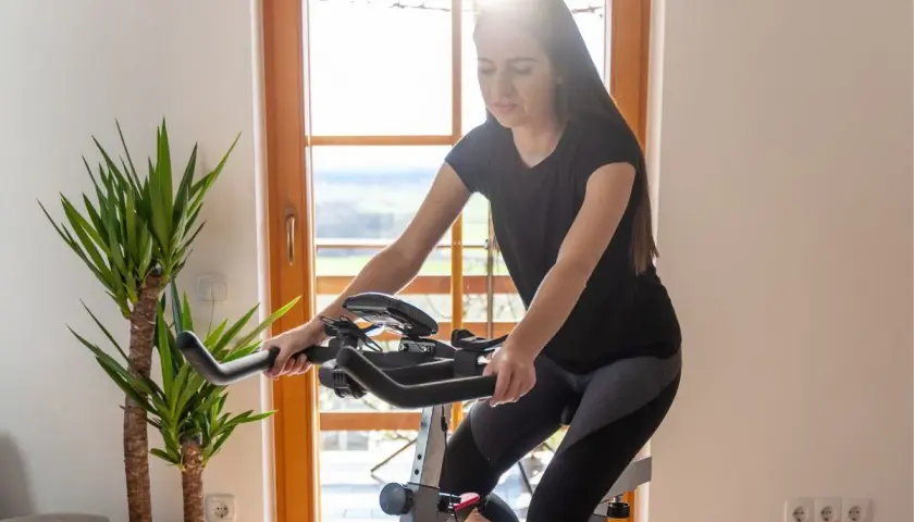 Młoda kobieta ćwiczy na rowerze stacjonarnym, szukając idealnego sprzętu jaki rower stacjonarny na odchudzanie.