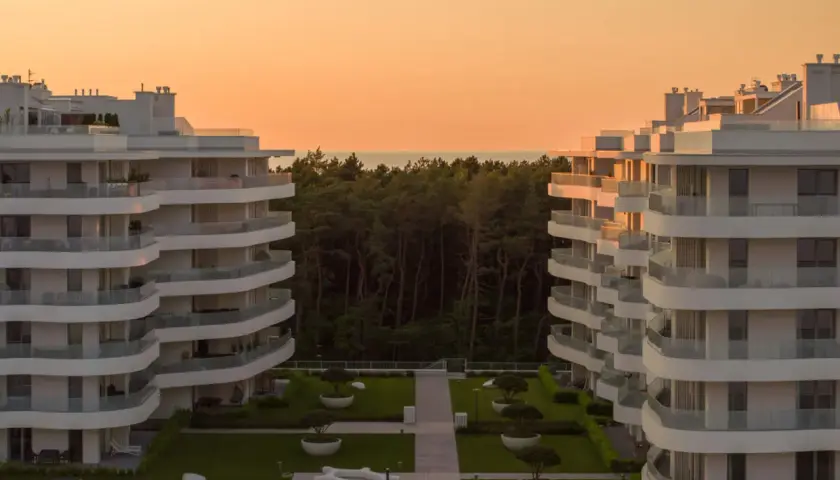 Nowoczesne apartamenty w Rogowie z widokiem na las i morze. Zachód słońca maluje niebo na pomarańczowo.
