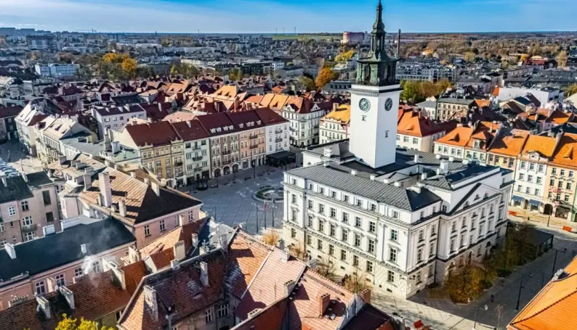 Widok na rynek z ratuszem i wieżą zegarową w najstarszym mieście w Polsce. Dachy kamienic tworzą malowniczy krajobraz.