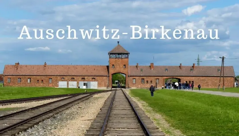Brama obozowa Auschwitz-Birkenau, gdzie historia przypomina o tragedii. Tłum zwiedzających podąża torami.