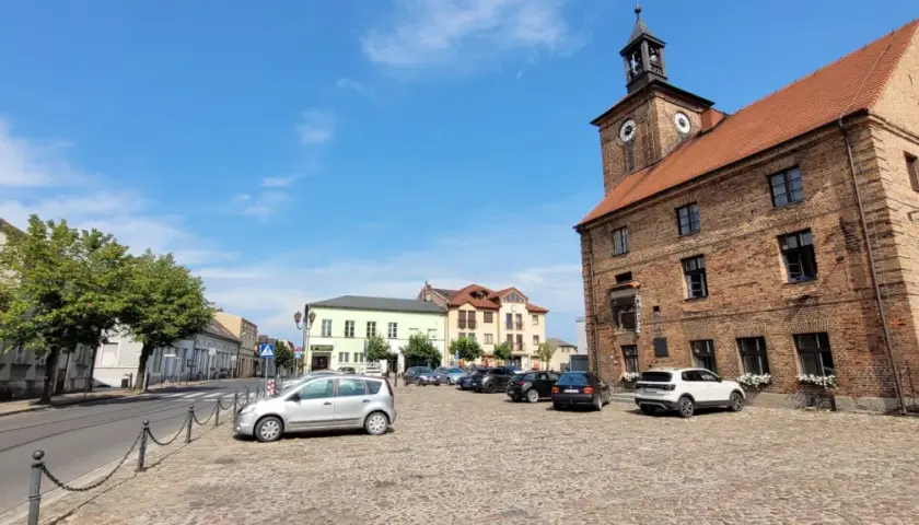 Rynek w Połajewie z ratuszem i kolorowymi kamienicami.