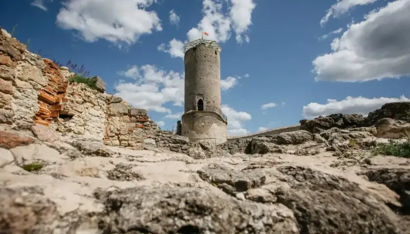 Kamienna wieża i ruiny zamku w Iłży pod błękitnym niebem z chmurami.