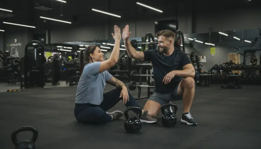 Para, którzy szukają crossfit Wrocław, gdzie można poczuć energię i wsparcie. Para świętuje sukces na siłowni.