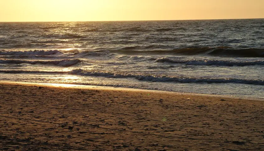 Piękny zachód słońca Sarbinowo. Złote światło odbija się od fal Bałtyku, tworząc magiczny widok na piaszczystej plaży.