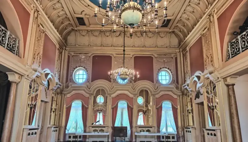 Wnętrze pałacu poznańskiego z bogatymi zdobieniami, dwoma żyrandolami i niebieskim sufitem.