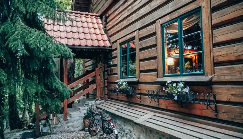 Drewniana chata z kwiatami w oknach i rowerem przy schodach. Idealne romantyczne miejsca Dolny Śląsk na wypoczynek.