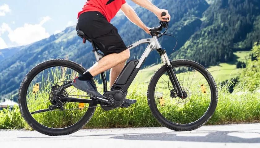Mężczyzna na rowerze elektrycznym w górach. Zastanawiasz się, jaki rower elektryczny wybrać? Ten model świetnie sprawdzi się na górskich trasach.