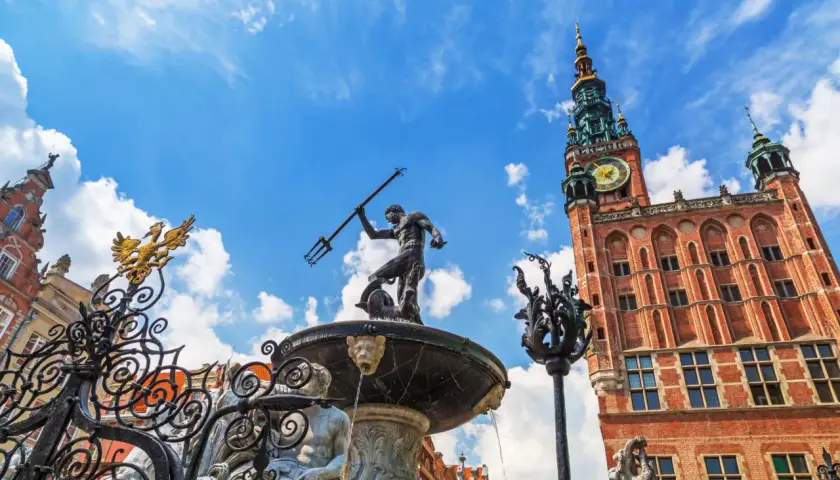 Fontanna Neptuna i Ratusz Głównego Miasta w Gdańsku Stare Miasto, pod błękitnym niebem.