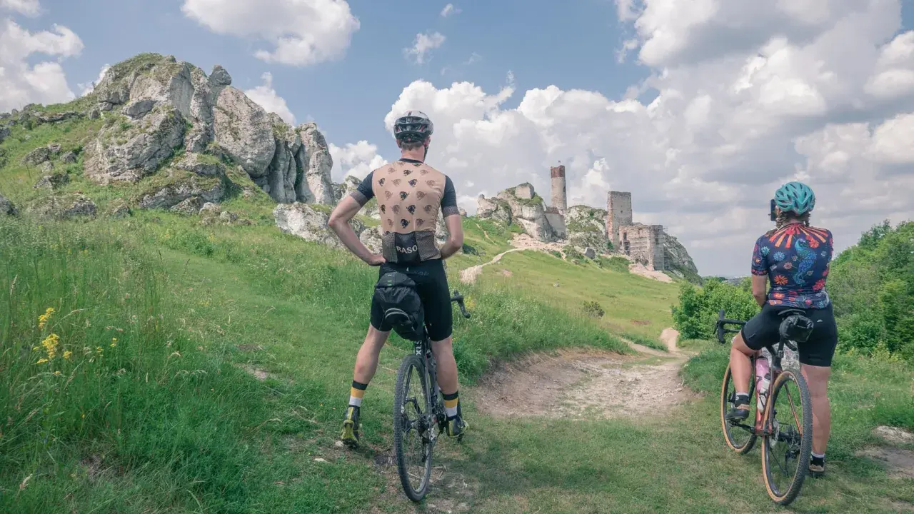 Dwaj rowerzyści podziwiają ruiny zamku na szlaku rowerowym Orlich Gniazd.