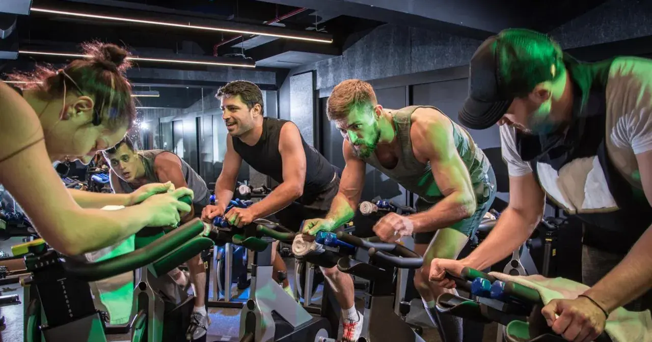 Intensywny trening spinningowy. Ludzie na rowerach stacjonarnych, skupieni na wysiłku.