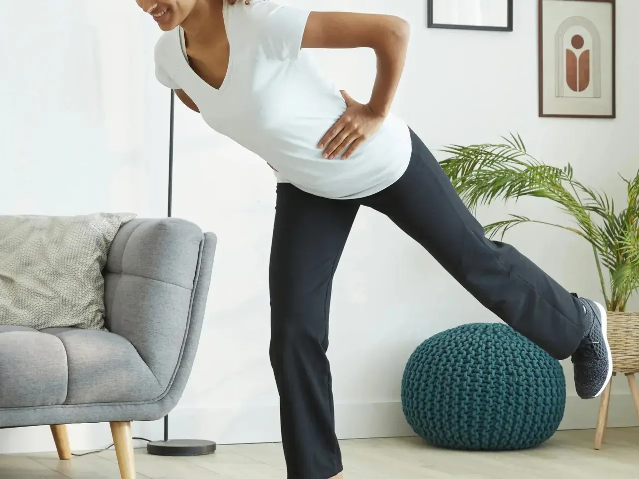Kobieta w ciąży ćwiczy pilates, unosząc nogę. Dba o formę i dobre samopoczucie.