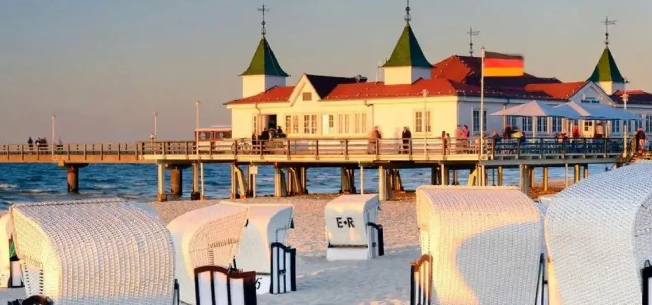 Plaża w Ahlbecku z molo i białymi koszami plażowymi. To popularne atrakcje nad Bałtykiem.