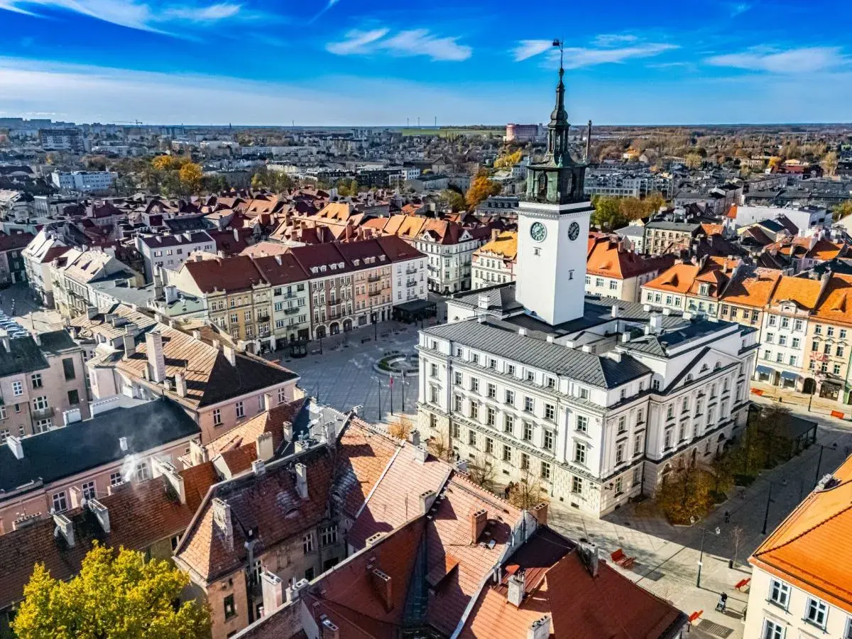 Widok na rynek z ratuszem i wieżą zegarową w najstarszym mieście w Polsce. Dachy kamienic tworzą malowniczy krajobraz.