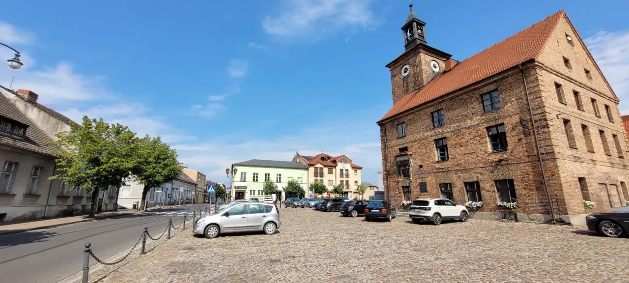 Rynek w Połajewie z ratuszem i kolorowymi kamienicami.