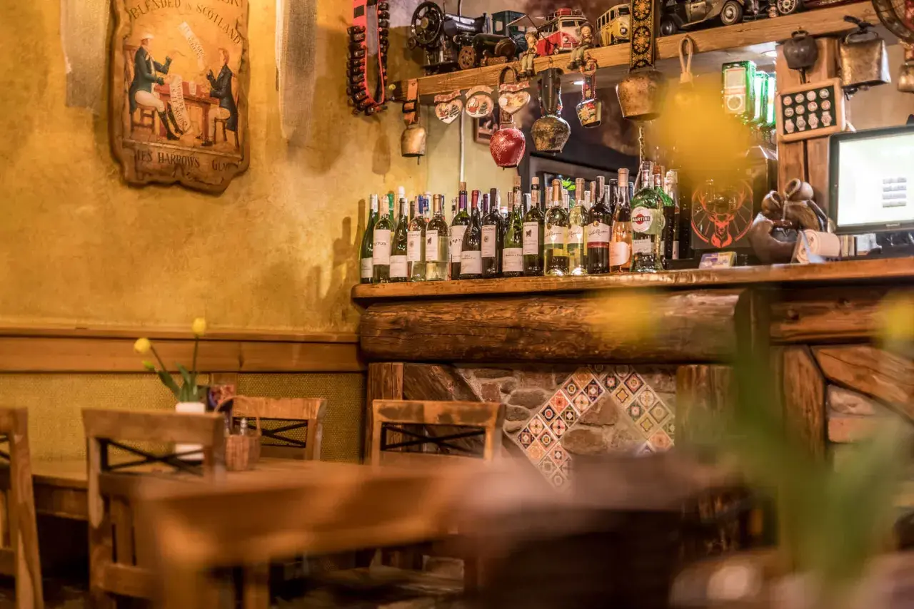 Drewniany bar w Szklarskiej Porębie Rynek, pełen butelek wina i ozdób.