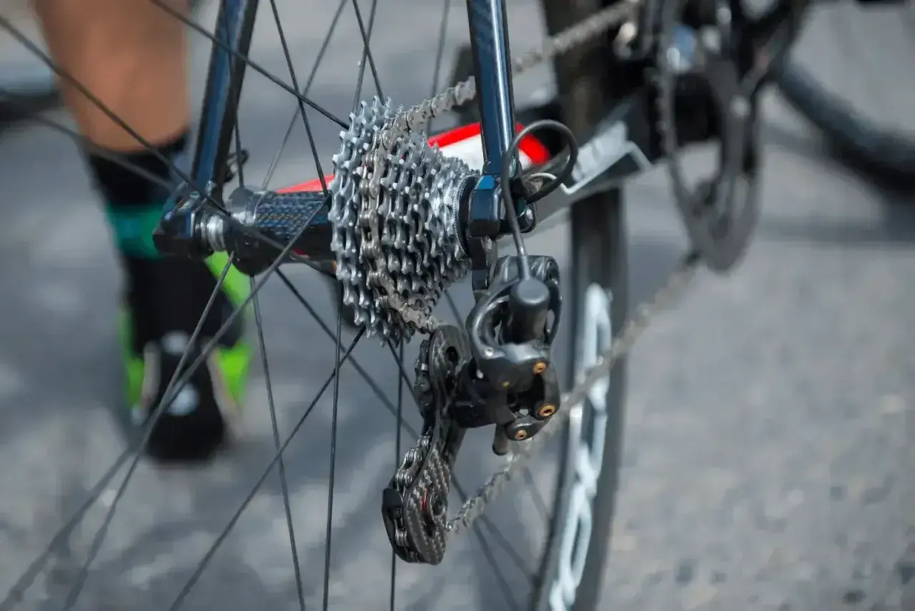 Jak naciągnąć łańcuch w rowerze z przerzutkami Shimano? Widok tylnego koła z kasetą i przerzutką.