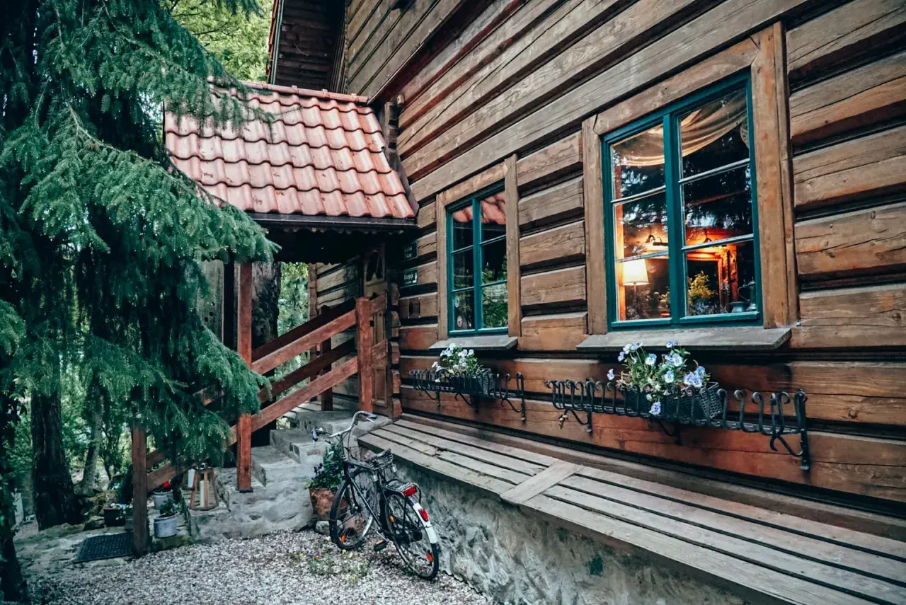 Drewniana chata z kwiatami w oknach i rowerem przy schodach. Idealne romantyczne miejsca Dolny Śląsk na wypoczynek.