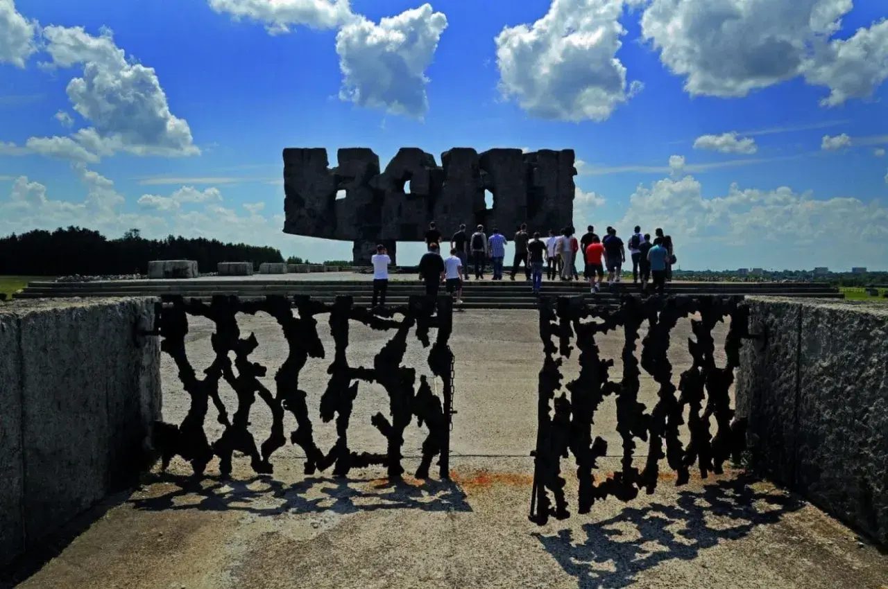 Brama pamięci na terenie byłego obozu Majdanek. Grupa ludzi zwiedza miejsce pamięci.