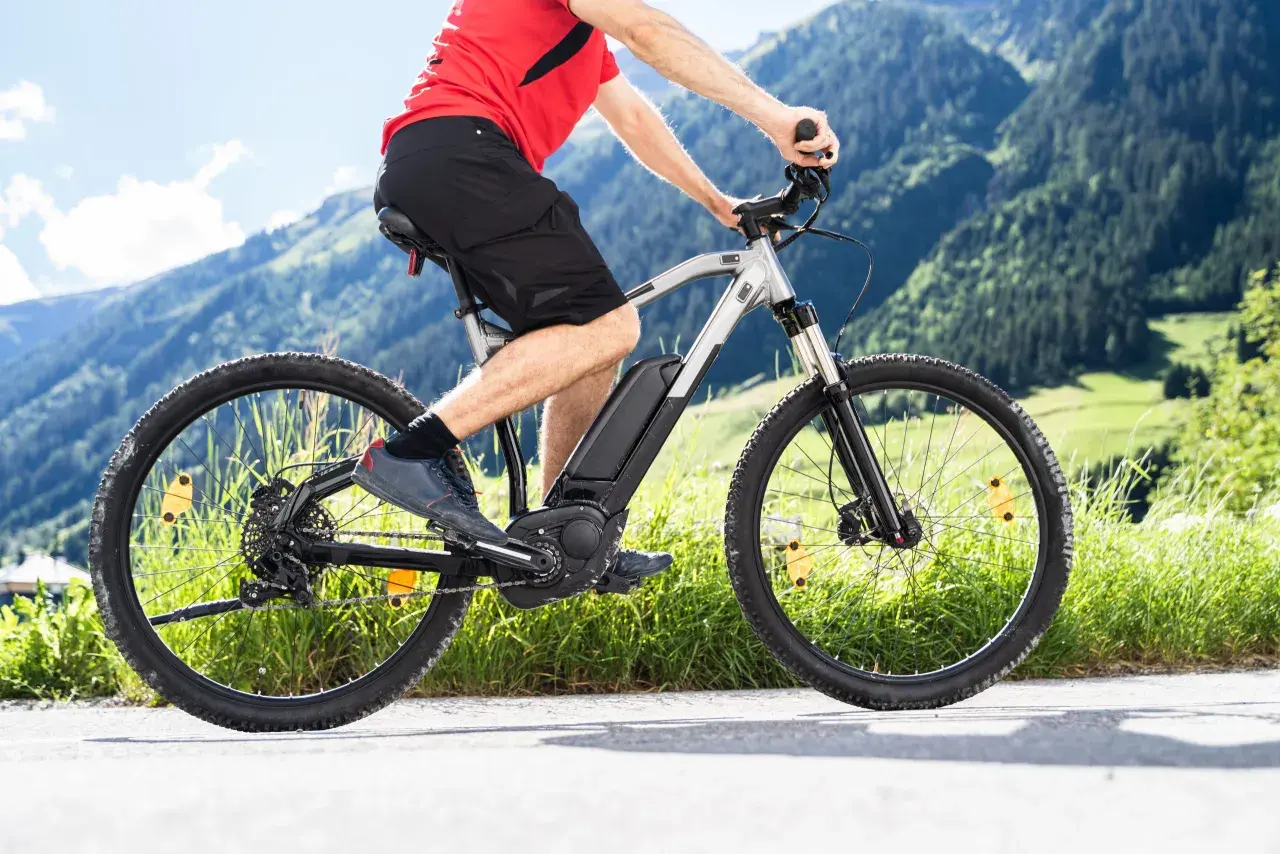Mężczyzna na rowerze elektrycznym w górach. Zastanawiasz się, jaki rower elektryczny wybrać? Ten model świetnie sprawdzi się na górskich trasach.