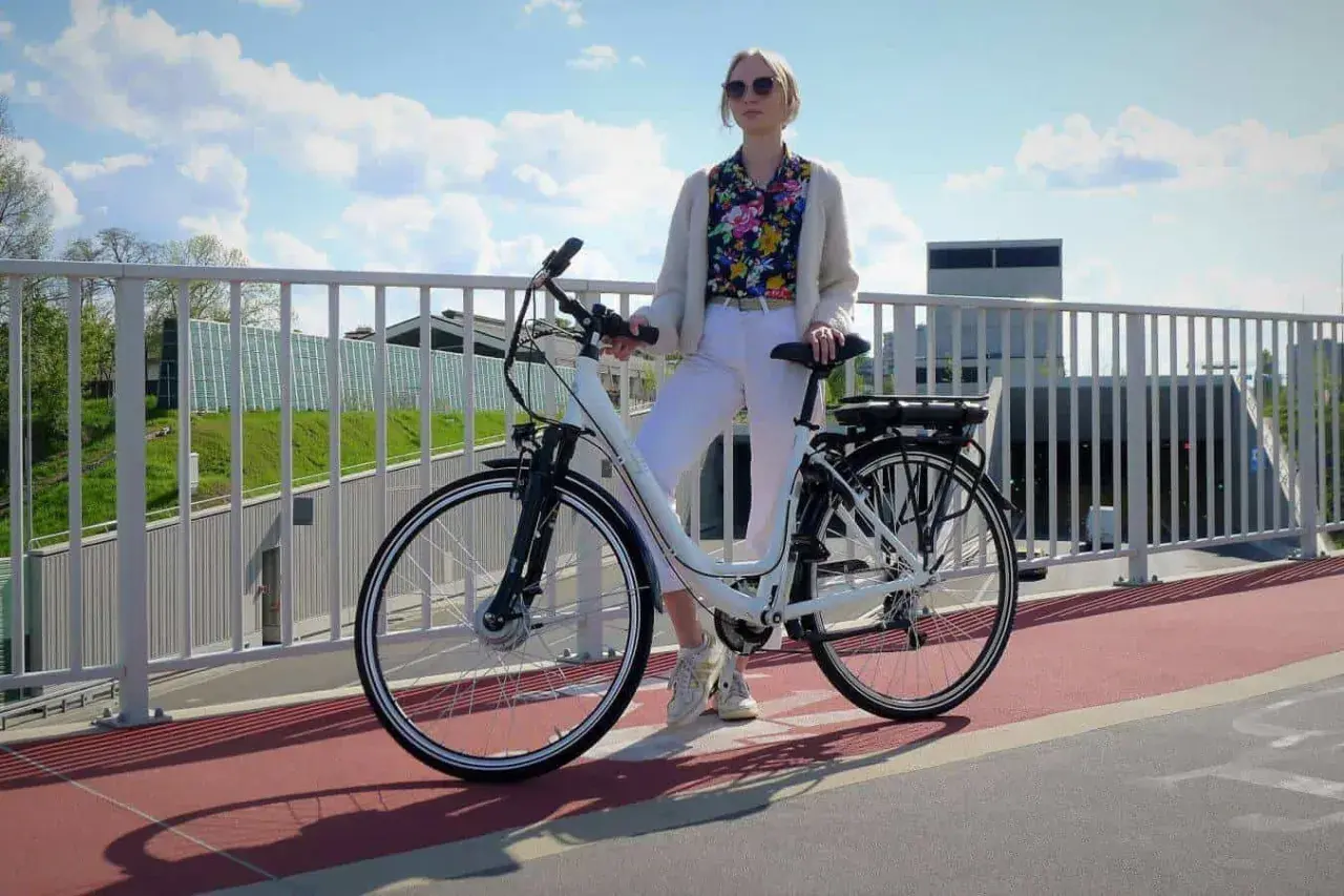 Kobieta z rowerem elektrycznym na moście. Czy na rower elektryczny trzeba mieć prawo jazdy? Zależy od jego mocy.