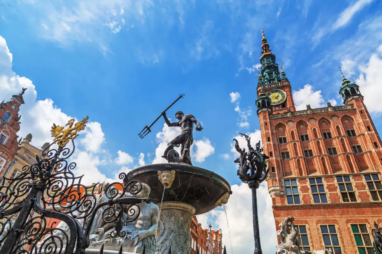 Fontanna Neptuna i Ratusz Głównego Miasta w Gdańsku Stare Miasto, pod błękitnym niebem.
