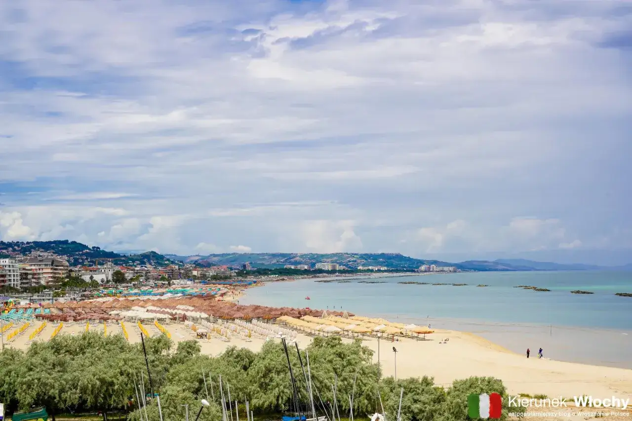 Pescara co zobaczyć: rozległa plaża z rzędami parasoli i leżaków, miasto w tle i spokojne morze. Idealne miejsce na wakacje.