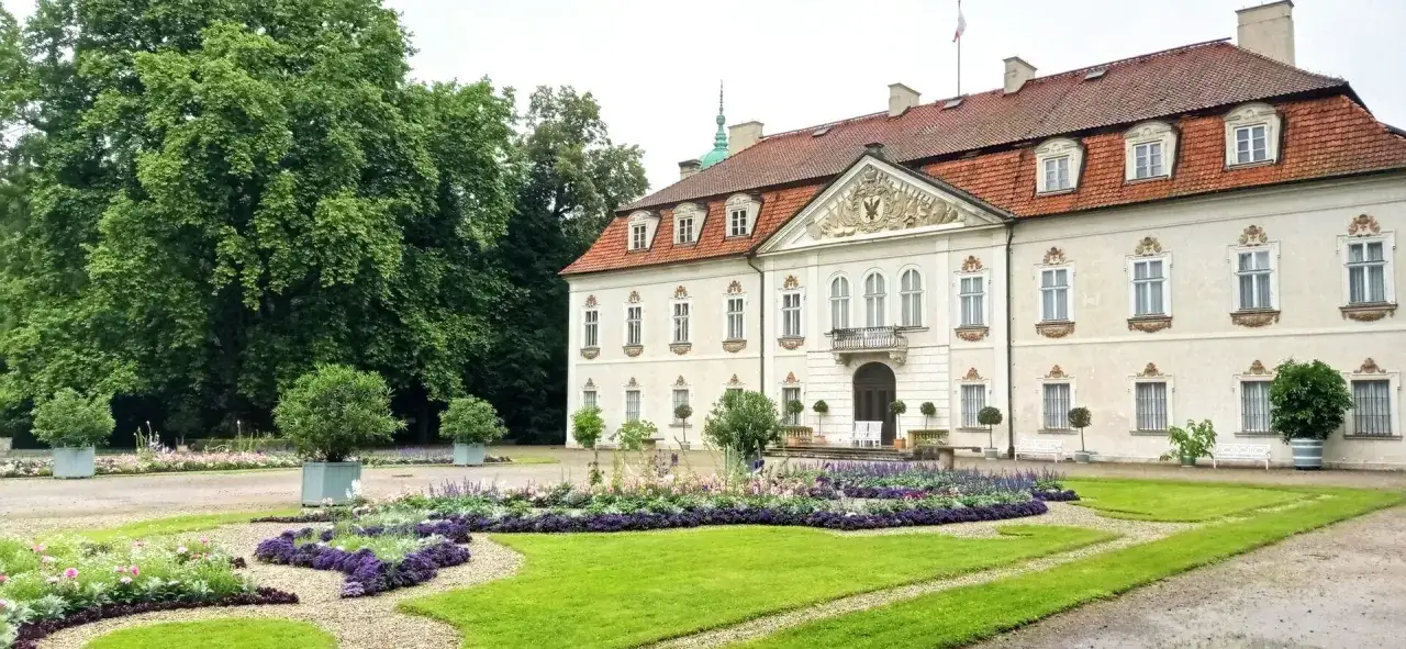 Pałac w Nieborowie otoczony kwitnącym ogrodem. Wspaniała architektura i zieleń tworzą malowniczy krajobraz.