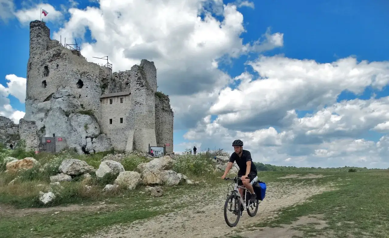 Rowerzysta na tle ruin zamku na Szlaku Orlich Gniazd.