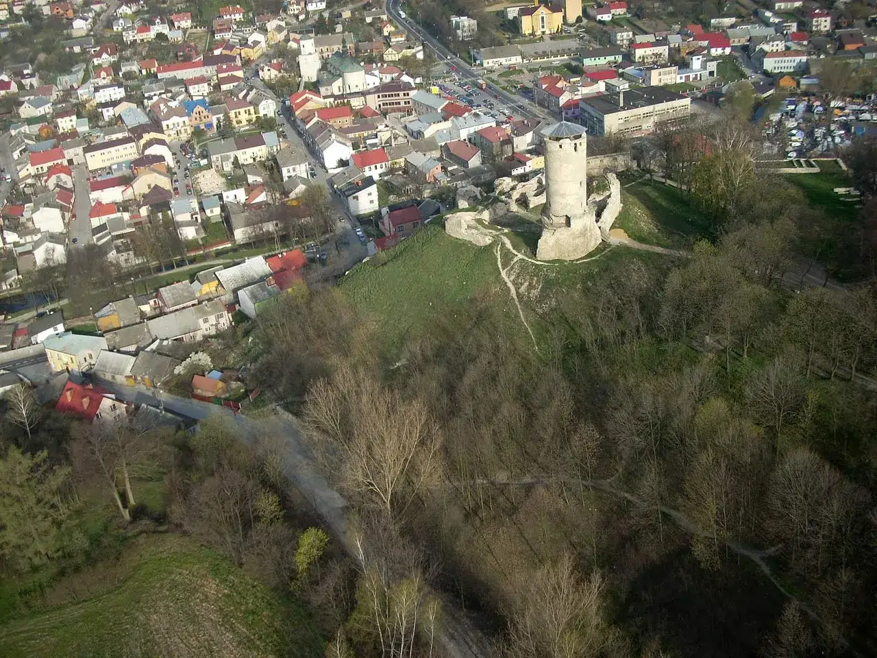 Widok z lotu ptaka na ruiny zamku w Iłży, otoczone przez miasto i las.