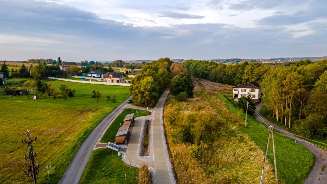 Nowy żelazny szlak rowerowy w otoczeniu zieleni i domów. Idealne miejsce na spokojną przejażdżkę.