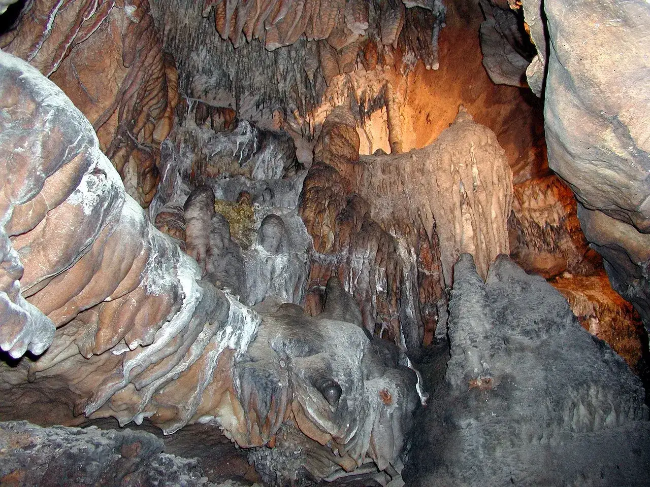 Wnętrze jaskini z naciekami, stalaktytami i stalagmitami. Grotołaz mógłby podziwiać te formacje skalne.