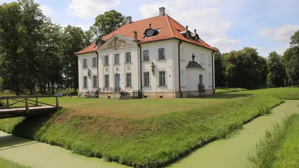 Pałac w Choroszczy otoczony fosą i zielenią. Drewniany mostek prowadzi do rezydencji.